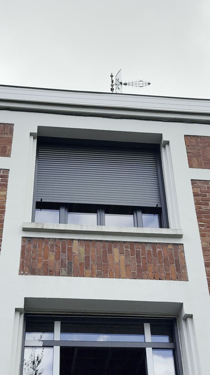 Coffres de volets roulants alignés au-dessus des fenêtres d'une façade