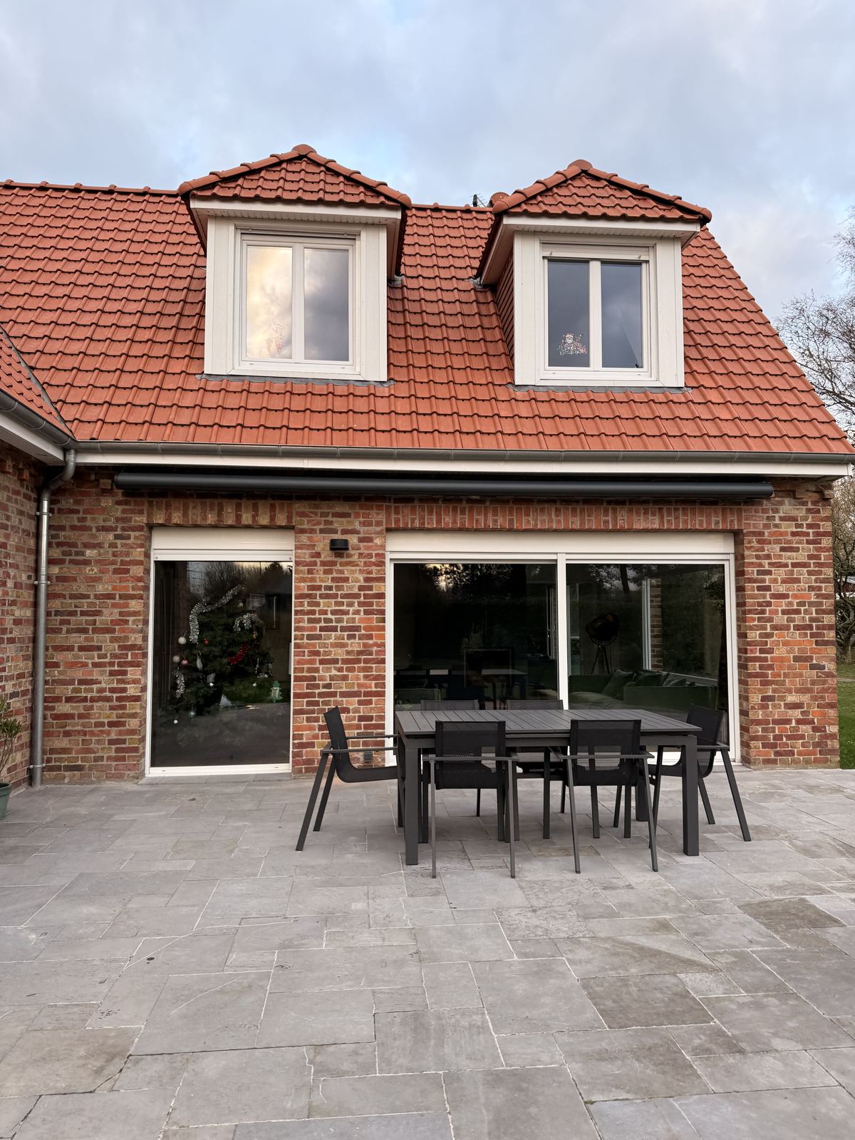 Maison en briques avec grandes baies coulissantes ouvrant sur une terrasse